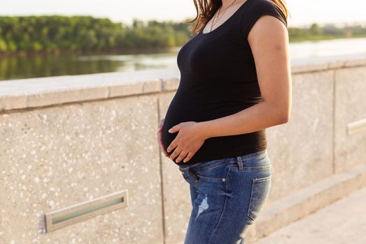 Close-up of pregnant belly outdoors. Pregnancy and motherhood