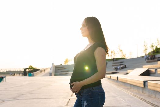 A Pregnant hispanic woman in the park, touching belly