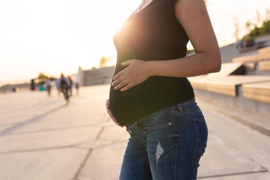 Close-up of pregnant belly outdoors. Pregnancy and motherhood