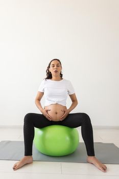 beautiful young pregnant woman doing exercise at home on fitball.