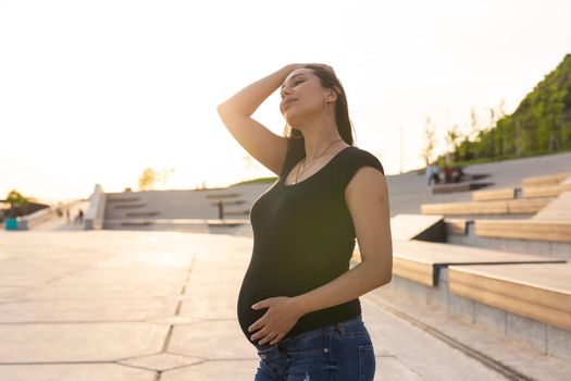 A Pregnant hispanic woman in the park, touching belly