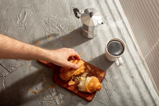 Breakfast with croissant on cutting board and black coffee. Morning meal and breakfast.