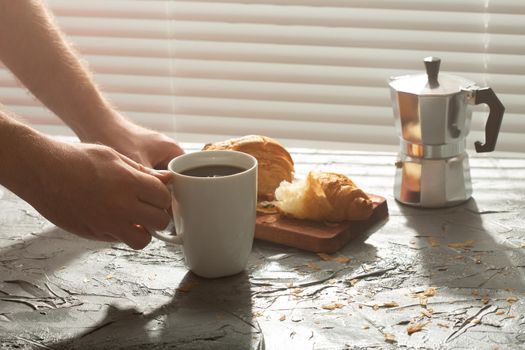 Breakfast with croissant on cutting board and black coffee. Morning meal and breakfast.