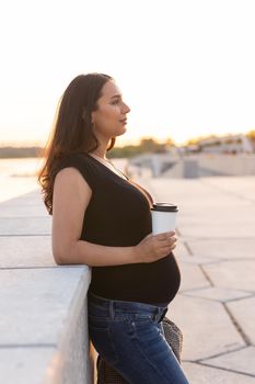 Beautiful young pregnant woman drinking take away coffee