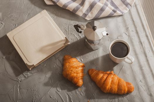 Breakfast with croissant on cutting board and black coffee. Morning meal and breakfast.