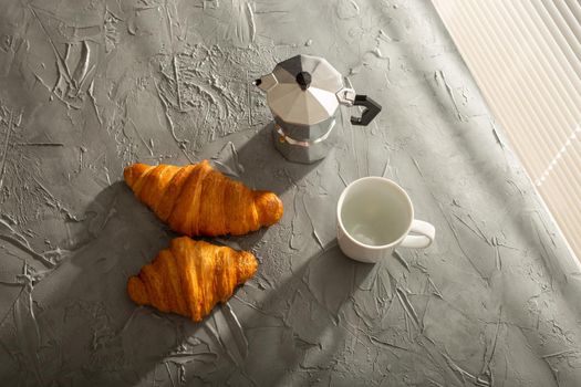 Breakfast with croissant on cutting board and black coffee. Morning meal and breakfast.