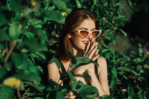 smiling woman wearing sunglasses green leaves nature fashion. High quality photo