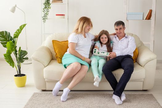 Family sitting on sofa in their living room. Daughter have injury hand but she is happy be together her family