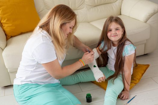 Mother and daughter drawing picture on bandage using paints. Play therapy concept