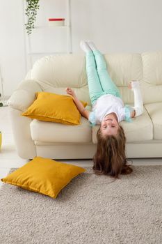 Child with a cast on a broken wrist or arm smiling and having fun on a couch. Positive attitude, recovery and kid.