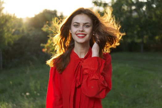 cheerful woman in a red dress in a field outdoors fresh air. High quality photo