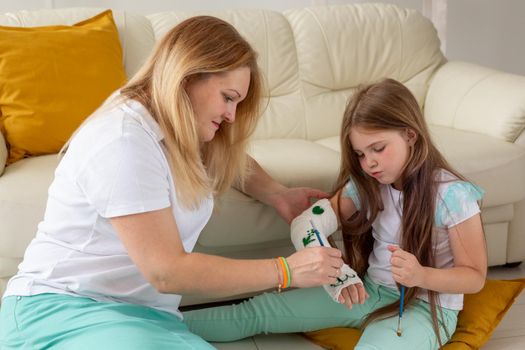 Mother and daughter drawing picture on bandage using paints. Play therapy concept