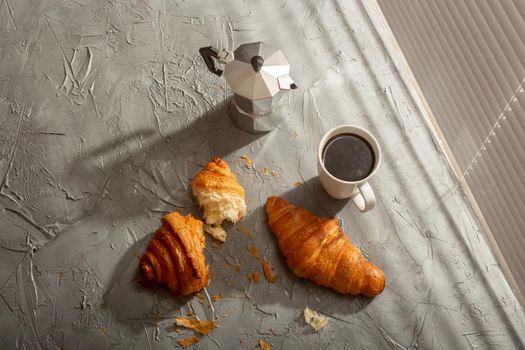 Breakfast with croissant on cutting board and black coffee. Morning meal and breakfast.