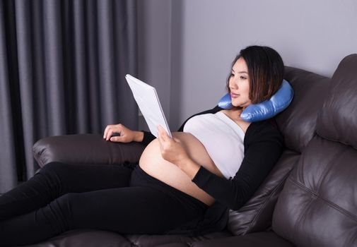 pregnant woman lying on sofa and reading a book