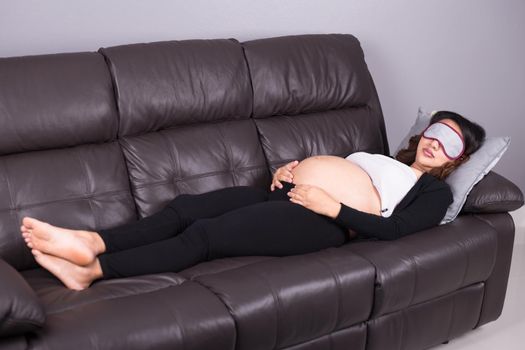 Pregnant woman sleeping on sofa in home