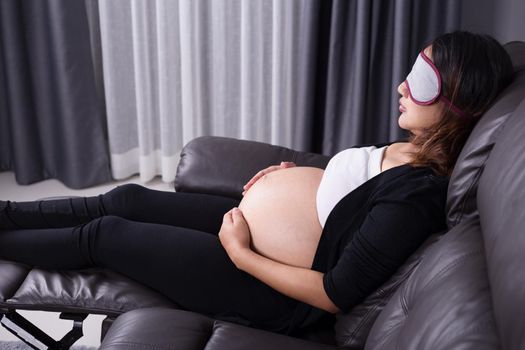 Pregnant woman sleeping on sofa in home