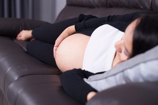 Pregnant woman sleeping on sofa in home