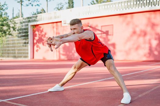 sports man in a red t-shirt on the sports ground doing exercises. High quality photo