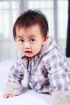 portrait of baby in jacket on a bed