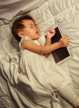 baby sleeping on bed after playing digital tablet