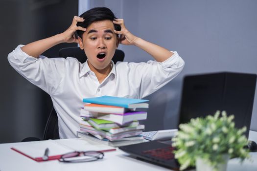 tired student sitting at the table with book and laptop