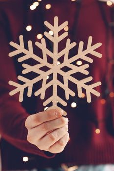 Female hands holding wooden snowflake, christmas decoration close up