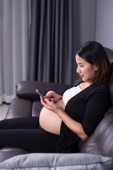 Portrait of pregnant woman using her mobile phone on sofa
