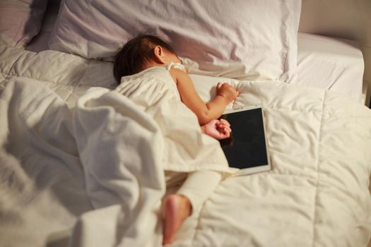 baby sleeping on bed after playing digital tablet