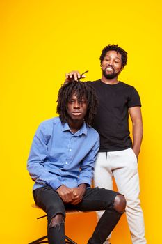 two african american guys posing cheerful together on yellow background, lifestyle people concept close up