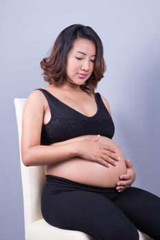 Beautiful pregnant woman on gray background