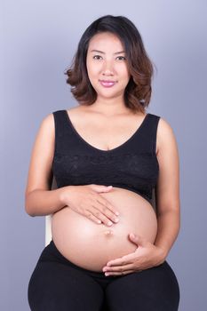 Beautiful pregnant woman on gray background