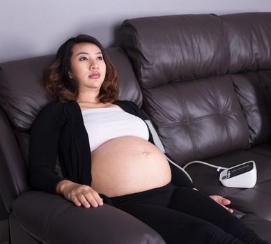 Pregnant woman measures blood pressure with automatic sphygmomanometer