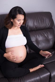 Pregnant woman sitting on sofa and holding her child ultrasound picture