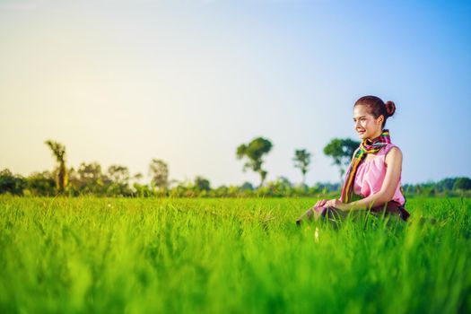 beautiful farmer woman sitting in green rice filed, Thailand