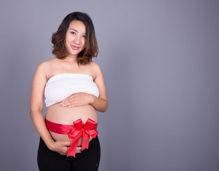 pregnant woman with red ribbon gift on belly