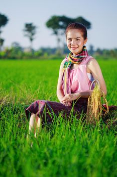 beautiful farmer woman sitting in green rice filed, Thailand
