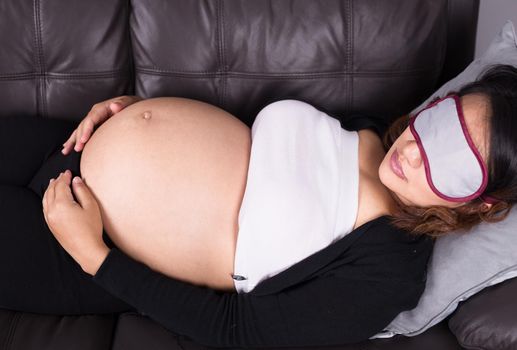 Pregnant woman sleeping on sofa in home