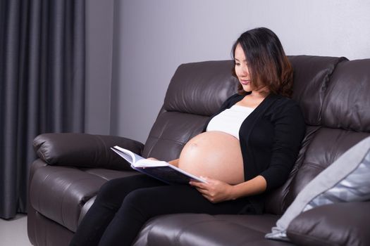 pregnant woman lying on sofa and reading a book