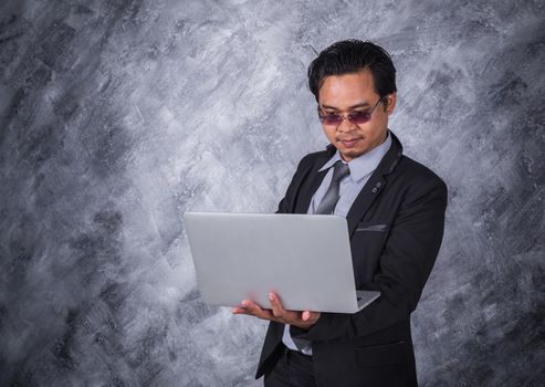 young business man holding laptop with wall background