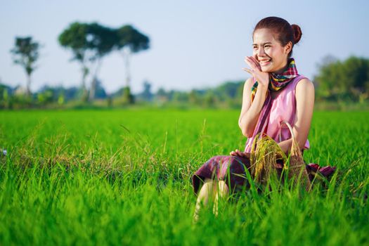 happy farmer woman sitting in green rice filed, Thailand