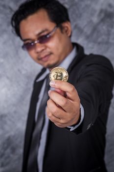 young man holding golden bitcoin in hand