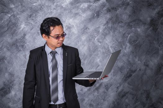 young business man holding laptop with wall background