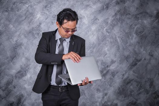 young business man holding laptop with wall background