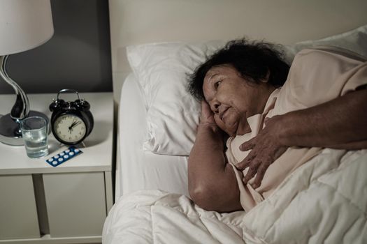 senior woman having heart problem in a bed at night