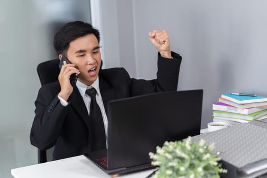 happy  young business man talking on mobile phone and using laptop