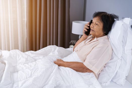 senior woman talking on mobile phone in a bed