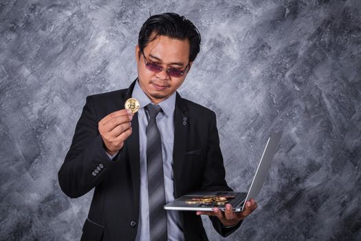 business man holding golden bitcoin with a laptop computer 