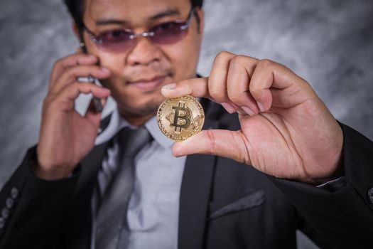 young business man with bitcoin and using mobile phone