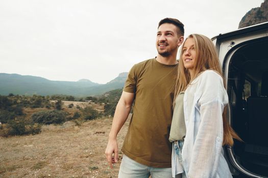 Young couple on road trip relaxing and enjoying the view of mountains