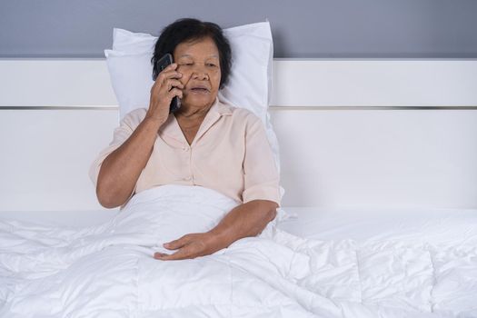 senior woman talking on mobile phone in a bed